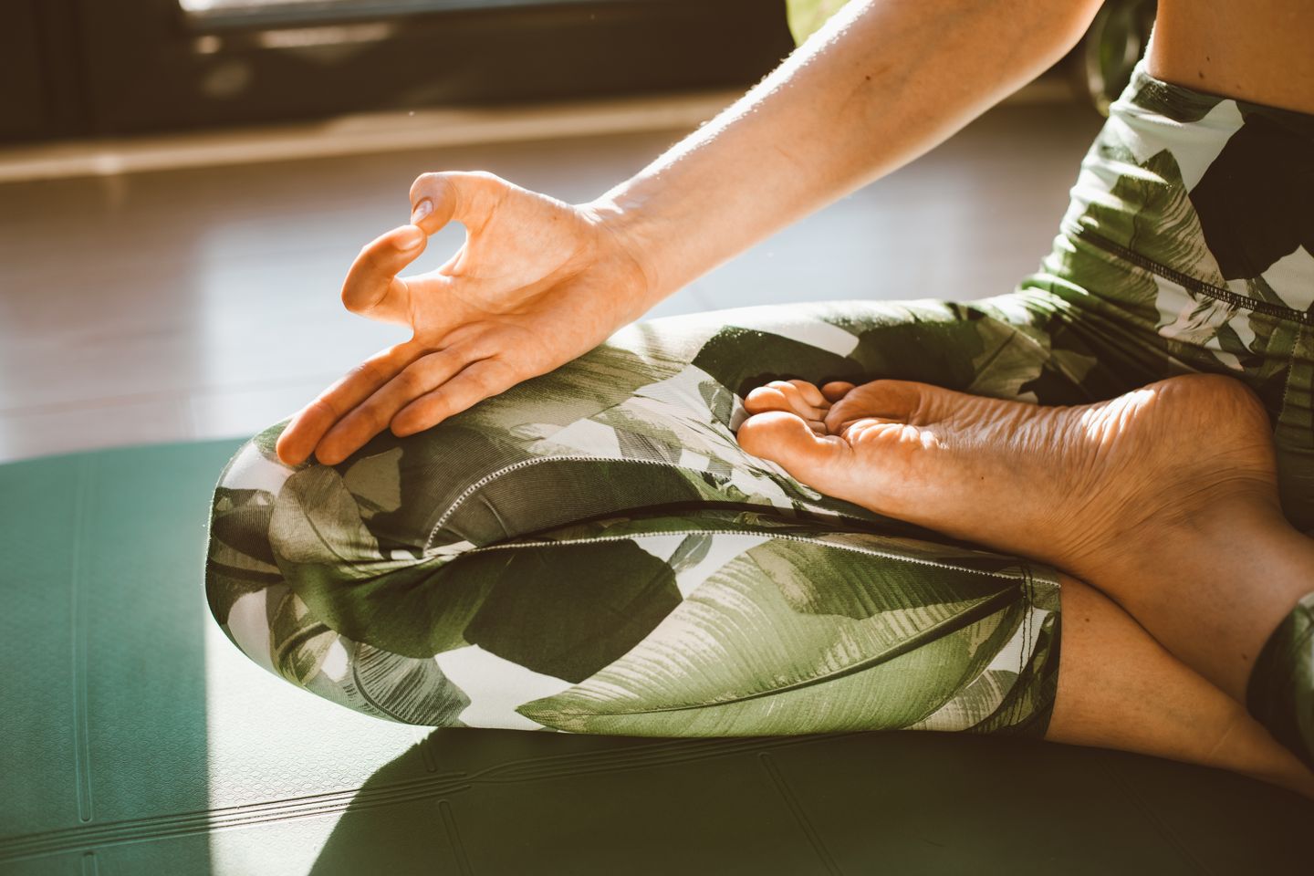 A person meditating in lotus position on a yoga mat, focusing on wellness and mindfulness.
